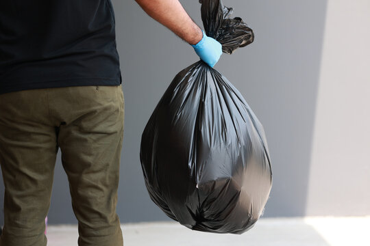 The Young Man Separated The Dangerous Waste Into A Large Black Bag And Put It In The Trash. The Correct Sorting Of Waste Household Waste