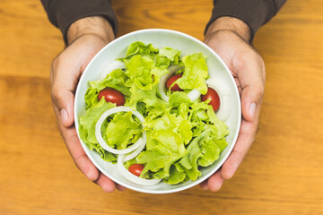 Hands holding bowl salad green oak and tomato. Breakfast diet menu. Fresh salad in morning