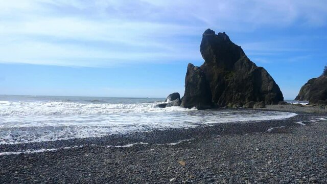 waves crash into a sea stack and then up the rocky beach at Ruby beach in Olympic National park, Washington