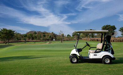 Golf cart on golf course, parking on fairway. Equipment and golf club bag are put in ready for golfer to player in field with sunlight rays background © APstudio