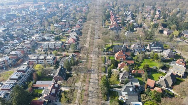 Aerial of oncoming car driving on a long road in a beautiful small town