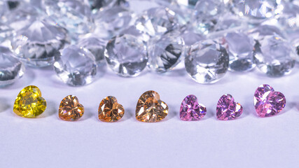colorful diamond in heart shape are placed in a row on white diamonds background,
