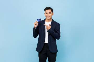 Nice handsome southeast Asian man in semi formal blazer holding credit card in light blue isolated studio background