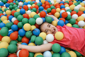 a child in the children's playroom. The girl is having fun among the colorful balls. Dry Pool Party