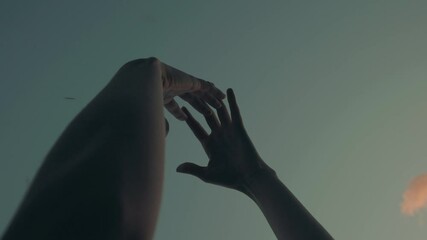 Arms raised to sky with hands slowly moving for ritual and leaves falling. Low angle Slow-motion