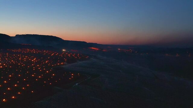 Beautiful Sunrise Aerial over Candles burning to heat up the Vineyards and the spraying of water to protect the buds in Chablis, France