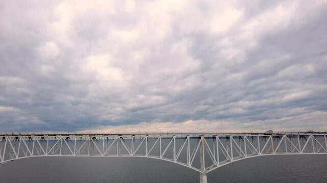Slow motion aerial footage of Westbound traffic on Route 50 crossing over Chesapeake Bay Bridge. Cars and trucks are passing over the sea on bridge