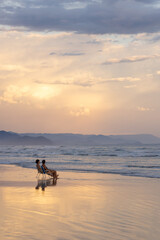 pessoas sentadas em cadeiras na praia vazia aproveitando o lindo final de tarde na praia de Bertioga. Conceito de tranquilidade e felicidade. 