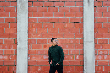 Fototapeta na wymiar portrait of male model with green military t-shirt on brick wall
