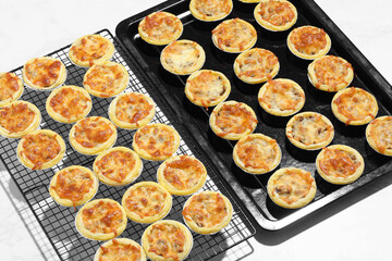 Mini pie from meat and mushrooms in metal tray on marble background