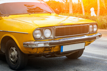 Obraz na płótnie Canvas Close up of the headlight, bumper, wheel, logo radiator grille, hood. old yellow rusted car