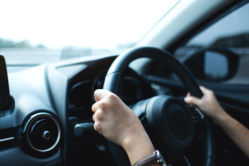 Naklejka premium Closeup image of a woman holding steering wheel while driving a car