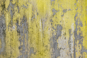 Old gray concrete wall with peeling yellow paint. Texture background.
