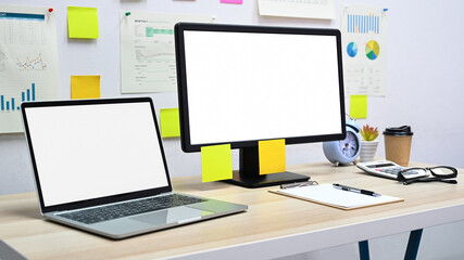Blank screen mockup computer and laptop with office equipment on the desk in the office.