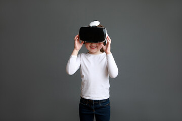 Preschooler in white long sleeve shirt wearing virtual reality glasses over grey background