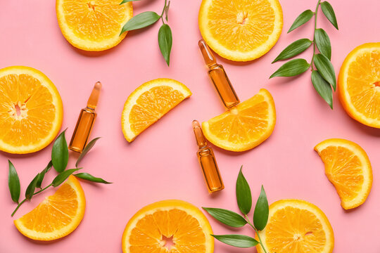 Ampules with vitamin C injection and orange fruit slices on color background