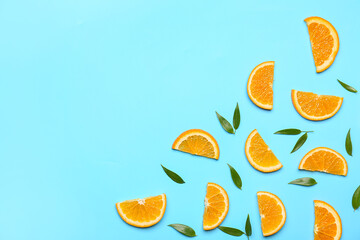 Slices of fresh oranges with green leaves on color background