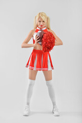 Beautiful cheerleader with rugby ball on light background