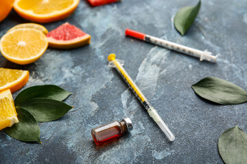 Fototapeta na wymiar Ampule with vitamin C, syringes and citrus fruits on color background
