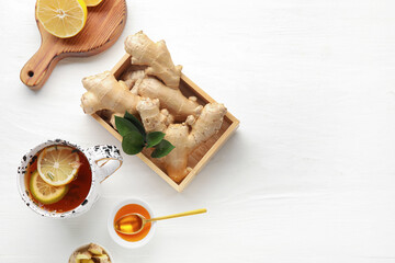 Composition with cup of tasty ginger tea and ingredients on light wooden background