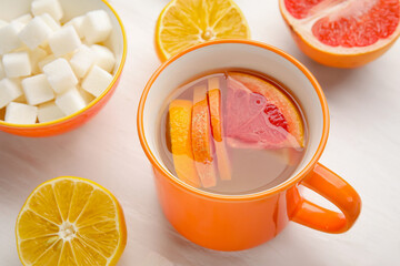 Cup of tasty ginger tea and ingredients on white background, closeup
