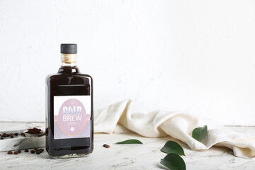 Bottle of cold brew, coffee beans and powder on light background