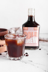 Composition with tasty cold brew and coffee beans on light background