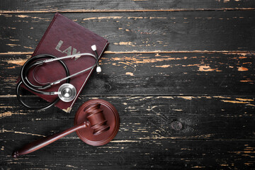 Judge gavel, book and stethoscope on wooden background. Concept of health care reform