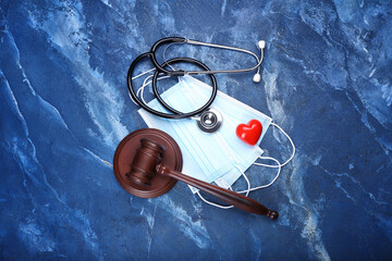 Judge gavel, masks, heart and stethoscope on color background. Concept of health care reform