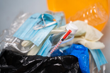 Closeup of Filed or over flowed single use Medical waste like face masks, gloves and syringe on...