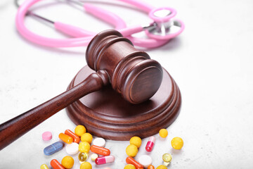 Judge gavel, pills and stethoscope on light background. Concept of health care reform