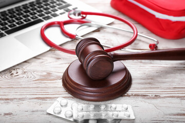 Judge gavel, pills, laptop and stethoscope on wooden background. Concept of health care reform