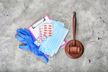 Judge gavel, pills, gloves and masks on grey background. Concept of health care reform