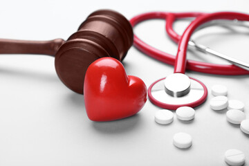 Judge gavel, heart, pills and stethoscope on white background. Concept of health care reform