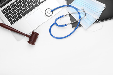 Judge gavel, laptop, masks and stethoscope on white background. Concept of health care reform