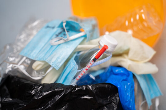 Closeup of Filed or over flowed single use Medical waste like face masks, gloves and syringe on garbage can or trash bin at hospital during coronavirus or covid-19 pandemic