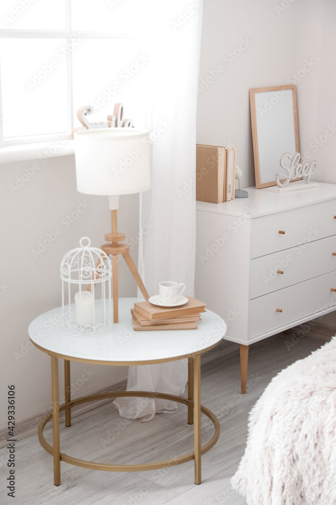 Wall mural Bedside table with lamp and cup of coffee in interior of modern room