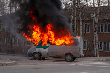Burning old minibus on the street. Fire in a car, ignition of electrical wiring.