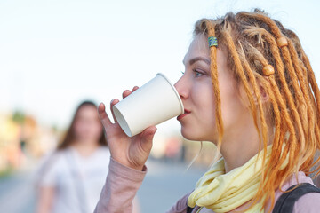 Portrait teenager woman with dreadlocks drinking coffee in paper cup
