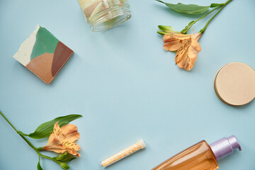 Female background concept on blue background. Cosmetic products and flowers