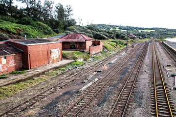 Obraz premium Old Railway Tracks with Dilapidated Unused Brick Buildings