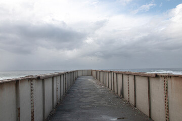 Fototapeta na wymiar Metal Pedestrian Bridge with the Sea as a Backdrop