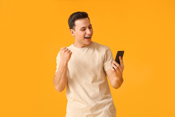 Happy young man with mobile phone on color background