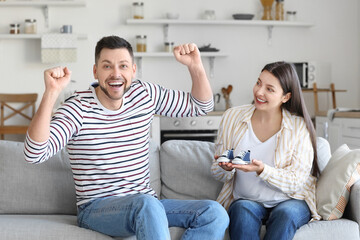 Happy pregnant couple with baby booties at home