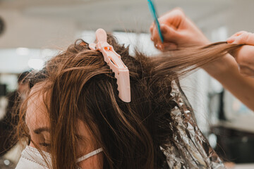 Hair coloring during the quarantine period, client and hairdresser in masks, hair bleaching.