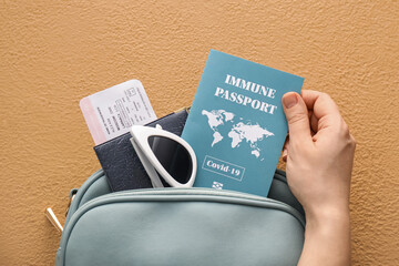 Tourist taking immune passport from bag on color background