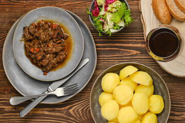 Overhead view of beef ragout with potato, salad and wine