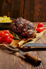Baked lamb leg on wooden cutting board with garnish