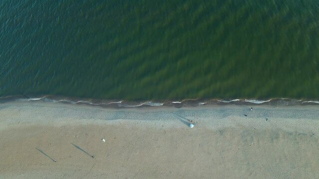 Aerial view from above person flying kite sail on calm sunny beach birds eye view