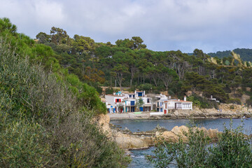 View of the white huts with doors and windows of different colors of the cove CALA S'ALGUER